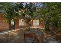 Secluded brick patio with wooden table and chairs, surrounded by lush greenery and a charming brick exterior at 5417 Carlton Rd, New Port Richey, FL 34652