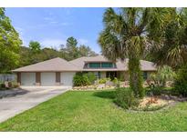 Charming single-story home with a three-car garage, a large manicured lawn, and mature landscaping at 6475 Laurel Oak Dr, Spring Hill, FL 34607