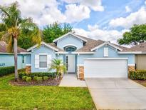 Charming single-story home featuring a well-manicured lawn and an attached two-car garage at 11050 Kiskadee Cir, New Port Richey, FL 34654