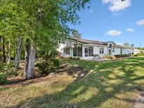 A home's backyard featuring a covered patio, a bench, and a beautiful grassy area at 11524 Holly Ann Dr, New Port Richey, FL 34654