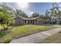 Charming single-story home featuring a well-manicured lawn, stone accents, and a two-car garage at 512 Winding Willow Dr, Palm Harbor, FL 34683