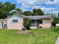 Charming pink single-story home featuring a screened porch and well-maintained lawn at 6045 Colony Cir, Weeki Wachee, FL 34607