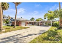 Spacious property featuring a red brick exterior, long driveway, and carport, surrounded by mature trees at 6552 River Rd, New Port Richey, FL 34652