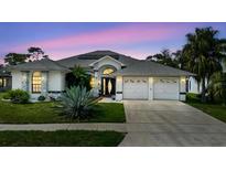 Beautiful home featuring a two-car garage, well-manicured lawn, and gorgeous front yard landscaping at 9301 Tournament Dr, Hudson, FL 34667