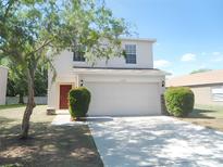 Charming two-story home with a well-maintained lawn, a two-car garage and a red entry door at 12431 White Bluff Rd, Hudson, FL 34669