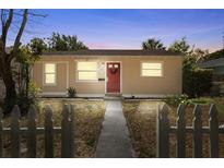 Charming single story home with a red front door and a well-manicured lawn, framed by a white picket fence at 1309 45Th S St, St Petersburg, FL 33711