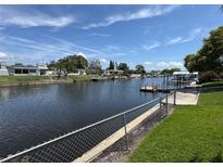 Beautiful waterfront view with backyard access to the canal and nearby boat docks under a partly cloudy blue sky at 1412 Linstock Dr, Holiday, FL 34690