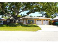Charming single story home featuring a mature shade tree, green grass, and a two car garage at 1540 Lime St, Clearwater, FL 33756