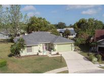 Well-maintained single-Gathering home featuring a manicured lawn, mature trees, and a two-car garage at 4647 Gazebo Ct, New Port Richey, FL 34655