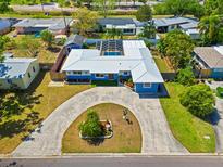 Aerial view of a stylish home with a screened pool, lush landscaping, and a circular driveway at 7230 17Th N Ln, St Petersburg, FL 33702