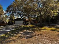 Charming home featuring mature trees, a spacious front yard, and a two-car garage at 8930 Phelps Rd, Hudson, FL 34667