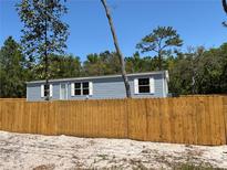 Charming single-story home with light blue siding and a newly installed wooden fence at 11444 Lake Dr, New Port Richey, FL 34654