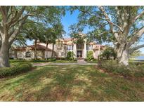 Stately two-story home featuring a lush front yard and a grand entrance framed by mature trees at 1473 Sail Harbor Cir, Tarpon Springs, FL 34689