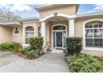 Charming home featuring a covered front entrance with classic columns and lush landscaping at 18328 Treehaven Dr, Hudson, FL 34667