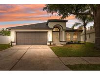 Charming single-story home featuring a manicured lawn, arched entry, and a spacious two-car garage at 18456 Merseyside Loop, Land O Lakes, FL 34638
