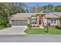 Charming single-story home with a well-manicured lawn, screened garage, and an inviting brick-accented entryway at 3013 Appleblossom Trl, Spring Hill, FL 34606