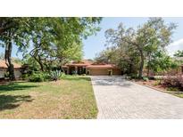 Charming single-story home featuring a brick driveway, mature trees, and beautiful landscaping at 4475 Rachel Blvd, Spring Hill, FL 34607