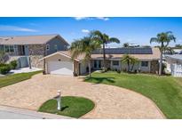 Charming home featuring solar panels, a brick driveway, well-manicured lawn and palm trees at 5033 Cabrilla Ct, New Port Richey, FL 34652