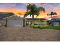 Charming home featuring a brick driveway, lush landscaping, solar panels and an attached two-car garage at 5033 Cabrilla Ct, New Port Richey, FL 34652