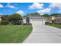 Charming single-story home boasts a well-manicured lawn and an attached two-car garage with a concrete driveway at 10109 Holly Berry Dr, Spring Hill, FL 34613