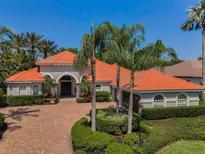 Stunning home featuring a clay tile roof, paver driveway and lush, tropical landscaping at 10712 Pontofino Cir, Trinity, FL 34655