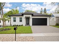 Charming single-story home featuring a manicured lawn, black garage door, and sleek modern design at 461 Pent St, Tarpon Springs, FL 34689