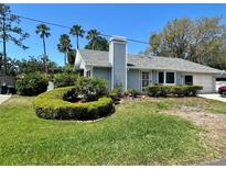 Charming single-story home featuring a well-manicured lawn and lush landscaping with palm trees and a winding walkway at 7444 Candlelight Ct, New Port Richey, FL 34652