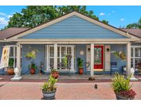 Charming home featuring a brick porch, vibrant red door, decorative plants, and a quaint window seat at 8516 Wooddrift Dr, Tampa, FL 33615