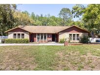 Charming single-story home features a brick facade, manicured lawn and mature trees at 10134 Buck Dr, New Port Richey, FL 34654
