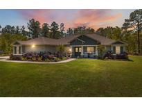 Charming single-story home with well-manicured lawn and landscaping at dusk at 11730 Hawks Nest Trl, Brooksville, FL 34614
