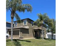 Lovely two-story home with an attached garage, beautiful landscaping, and mature palm trees at 11796 Crestridge Loop, New Port Richey, FL 34655