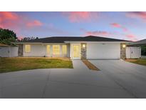 Charming single-story home with a well-manicured lawn and a two-car garage at dusk at 1216 Yawl Way, Venice, FL 34285