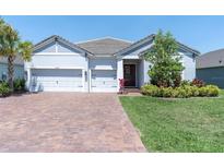 Welcoming single-story home with a brick driveway, three-car garage, and professionally landscaped front yard at 12617 Wetmore Ct, Odessa, FL 33556