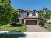 Charming home featuring a stone facade, a two car garage, and landscaped front yard at 2431 Murray Pass, Odessa, FL 33556
