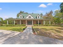 Charming single-story home boasts a wide porch, a green roof, and a well-manicured lawn at 3431 Saturn Rd, Brooksville, FL 34604