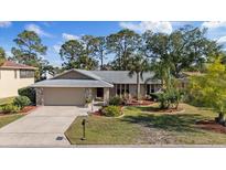 Charming single-Gathering home featuring a manicured lawn, mature trees, and an attached two-car garage at 4504 Dewey Dr, New Port Richey, FL 34652