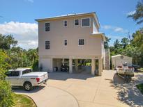 Stunning waterfront home featuring an open air ground floor, a driveway, and lush landscaping at 4514 Fishman Ave, Weeki Wachee, FL 34607