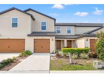 Inviting two-story townhome featuring a well-maintained lawn, attached garage, and neutral color palette at 5383 Companion Ln, Tampa, FL 33619