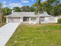 Charming single-story home featuring an attached two-car garage, a well-manicured lawn, and mature landscaping at 5411 Joyner Ave, Spring Hill, FL 34608
