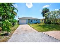 Charming one-story home with a well-manicured lawn, bright blue paint, and a long driveway at 6432 Boatyard Dr, Hudson, FL 34667