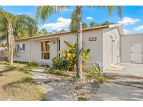 Charming single-story home featuring palm trees, a light gray exterior, and inviting landscaping at 7365 Pinehurst Dr, Spring Hill, FL 34606