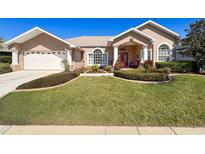 Charming home with well-maintained lawn, mature landscaping, and inviting red double-door entrance at 8523 Regal Ln, Hudson, FL 34667