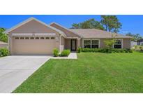 Well-maintained single-story home featuring a manicured lawn, attached two-car garage, and meticulously designed landscaping at 11310 Limpkin Rd, Weeki Wachee, FL 34614