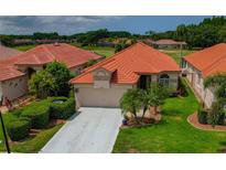 Beautiful single-story home with a well-manicured lawn, lush landscaping, and a red tile roof at 1260 Dartford Dr, Tarpon Springs, FL 34688