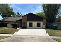 Charming single-story home with a brick accent wall, black trim, and a large concrete driveway leading to a two-car garage at 1412 Wexford N Dr, Palm Harbor, FL 34683