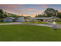 Expansive single-story home with lush lawn, circular driveway, and a three-car garage at 2400 Commack Ct, New Port Richey, FL 34655