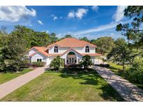 Beautiful white home features manicured lawn, two story construction and tile roof at 5198 Legend Hills Ln, Brooksville, FL 34609