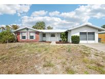 Inviting single-Gathering home with an attached garage, complemented by a neatly kept yard and clear blue skies at 10309 Honeysuckle Ln, Port Richey, FL 34668
