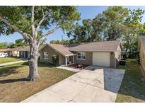 Charming single-story home featuring a well-maintained lawn, mature trees, and a private driveway at 12708 River Mill Dr, Hudson, FL 34667