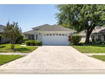 Charming single-story home featuring a well-manicured lawn, brick driveway, and a welcoming two-car garage at 14105 Agua Clara Dr, Hudson, FL 34667